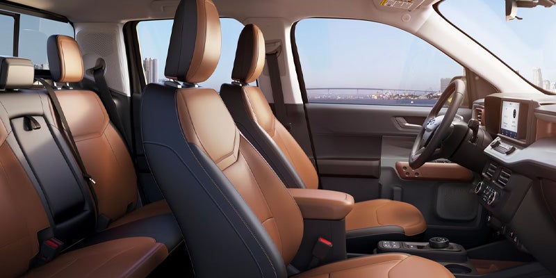 Interior view of a car with brown and black two-tone seats and a city skyline visible through the windows.